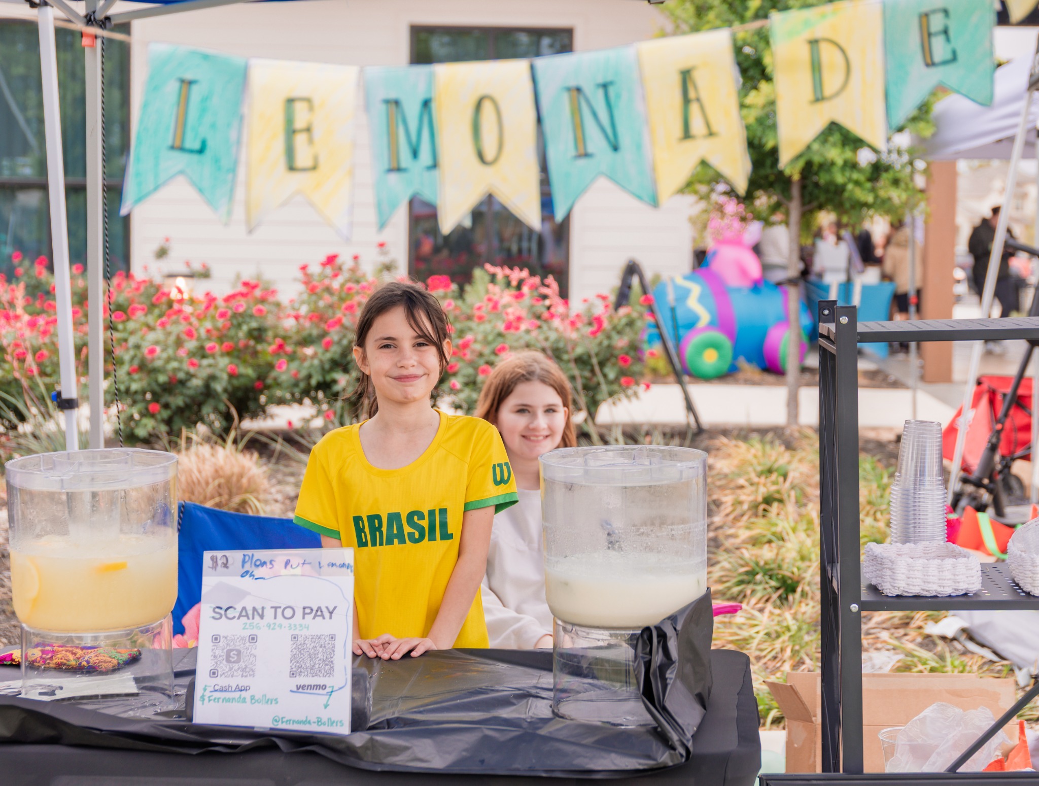 Young vendors smiling behind a lemonade stand