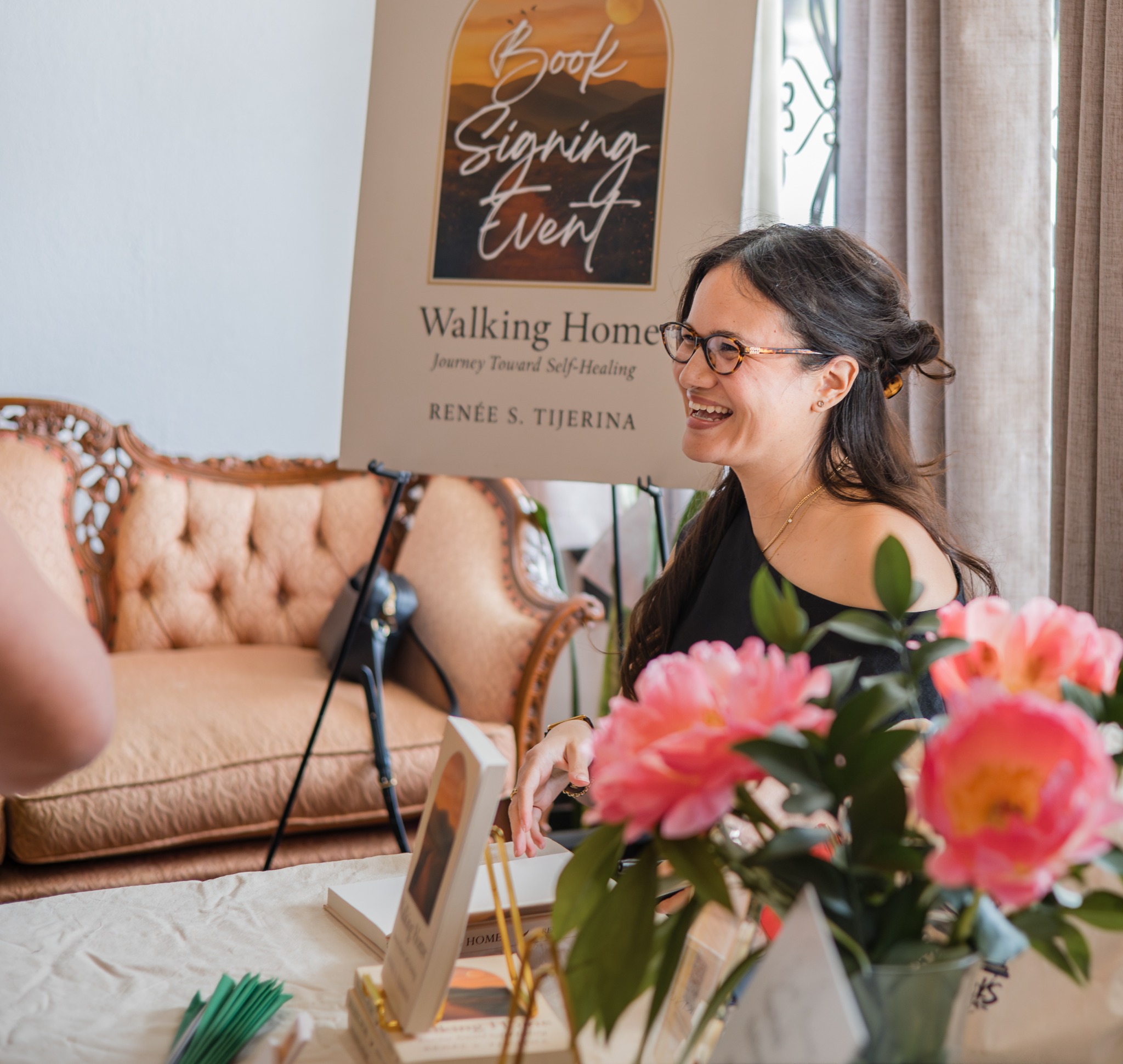 Author interacting with a guest with event signage and flowers visible