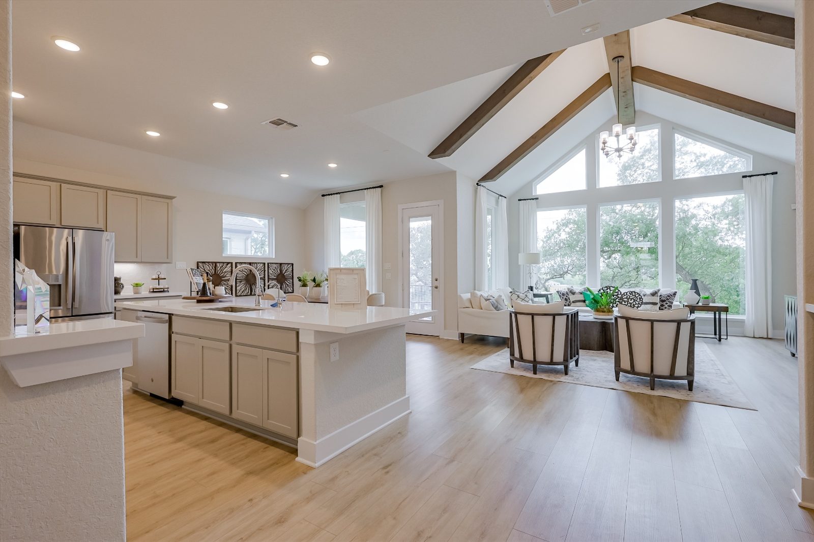 Kitchen island opening into living room with large windows