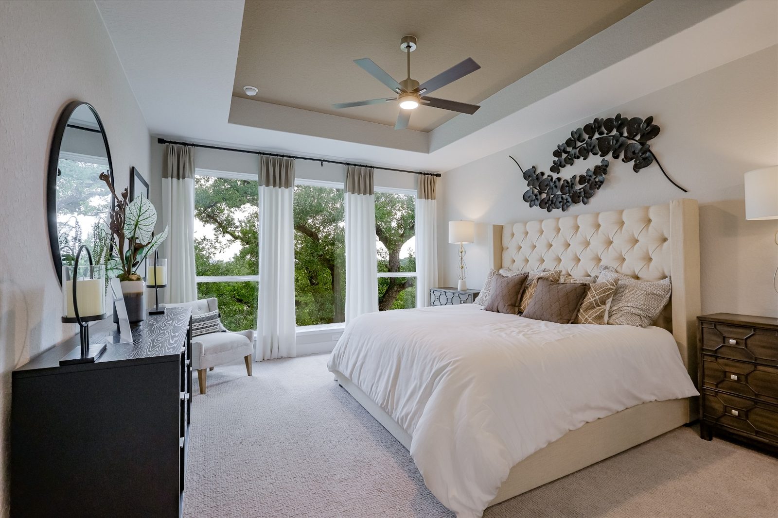 Primary bedroom with tray ceiling and tree-view windows
