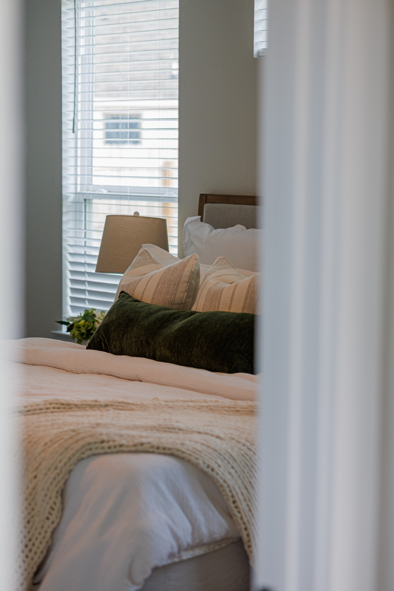 Layered pillows and bedding beside a bright window
