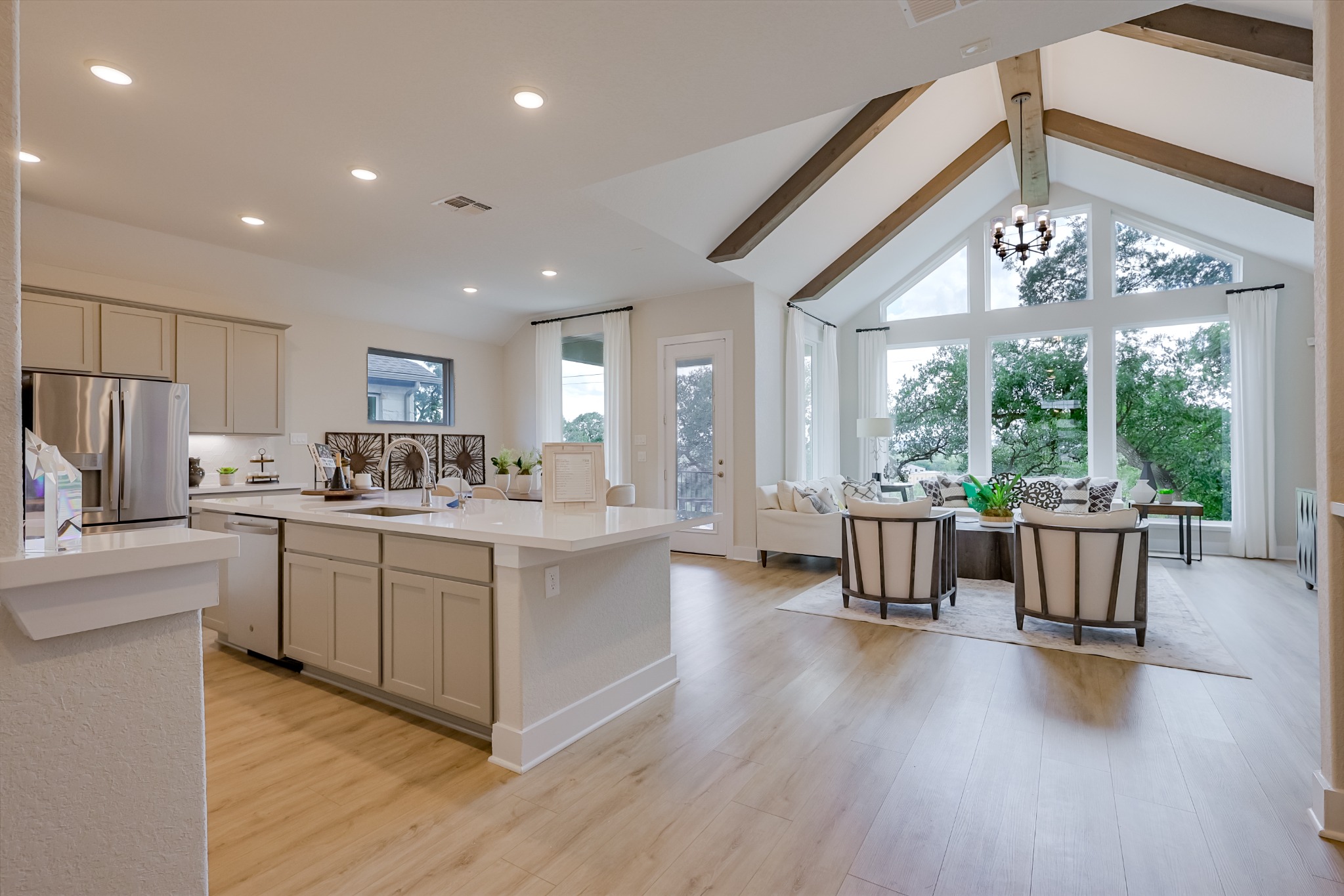 Kitchen island opening into living room with large windows